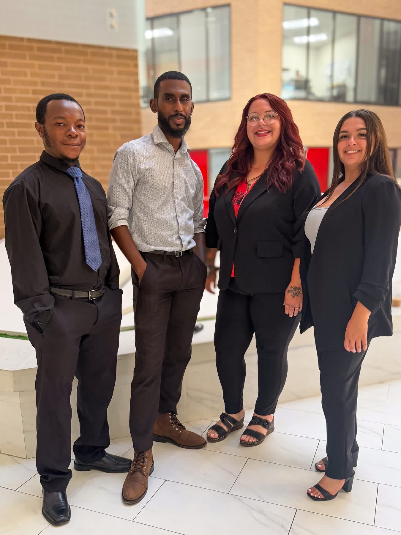 Four ScorpCo team members standing together in a bright atrium